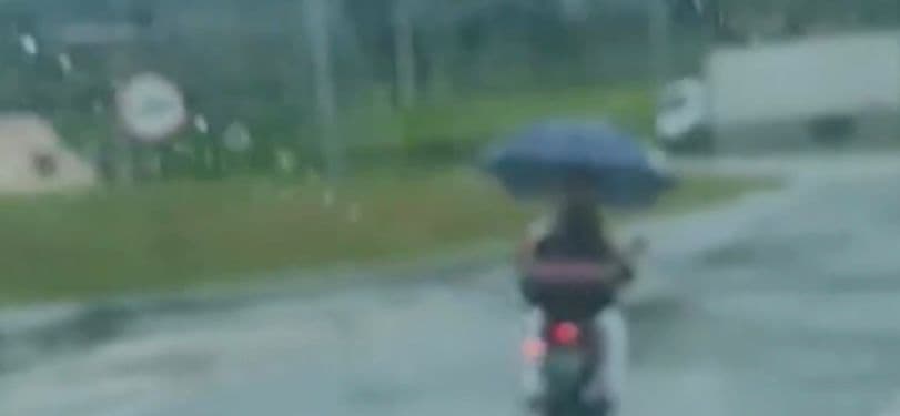 Motociclista é flagrado andando de moto segurando guarda-chuva em dia de chuva e causa preocupação com segurança no trânsito